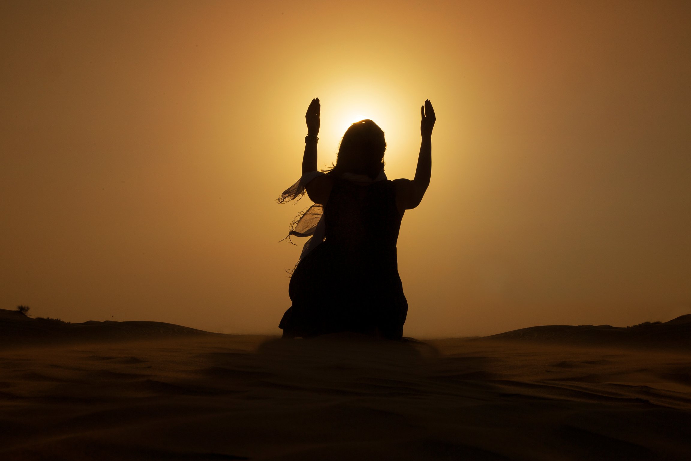 Silhouette of praying women at desert